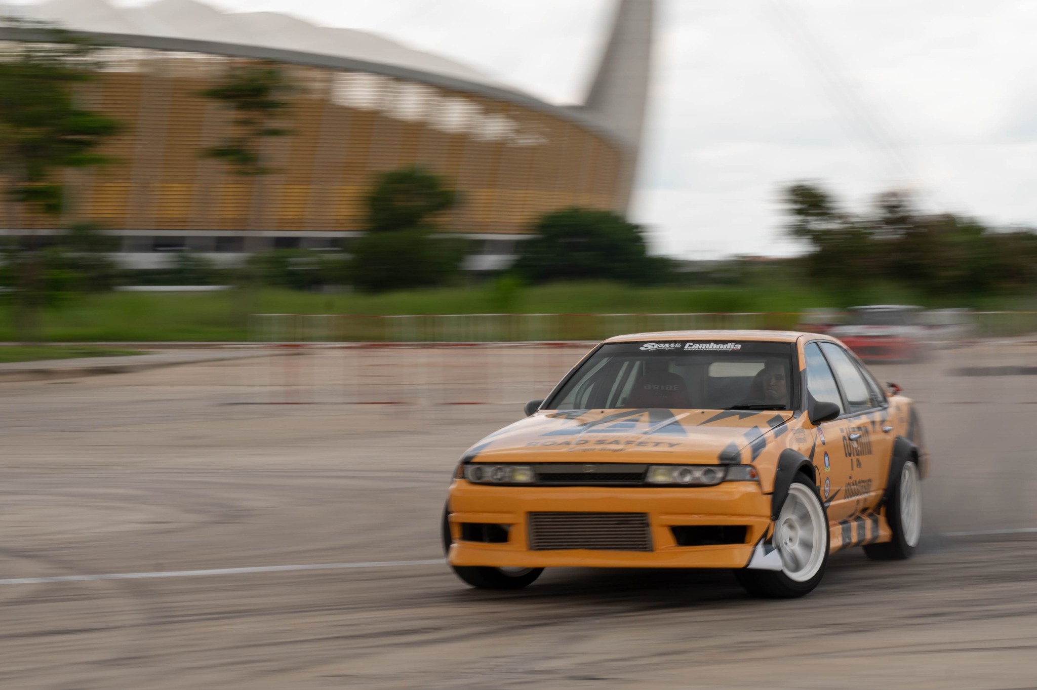 Orange Nissan Silvia drifting with Morodok Techo Stadium in background