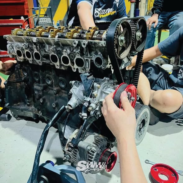 Team assembling the inline-6 -- timing belt and pulleys